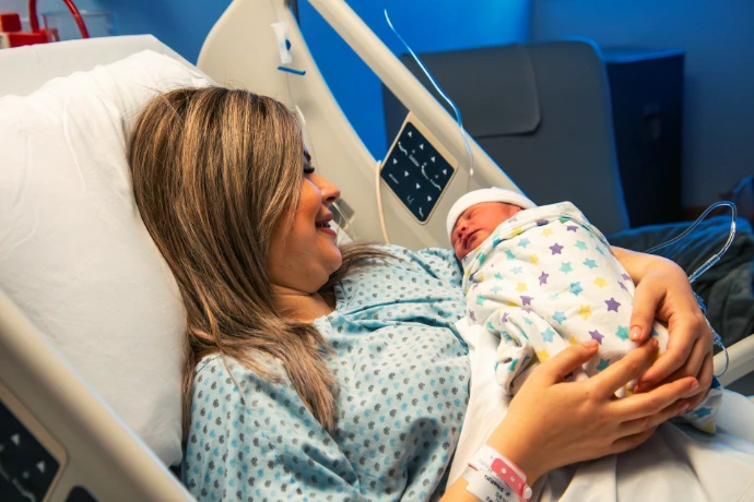 A woman holding a baby in a hospital bed